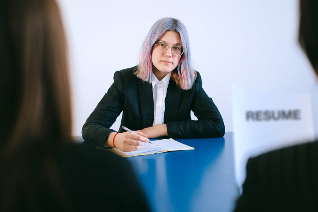 A young woman with dyed hair takes notes during a job interview.